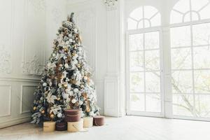 klassische weihnachten neujahr dekoriert innenraum neujahrsbaum. Weihnachtsbaum mit Goldschmuck. Moderne weiße Innenarchitekturwohnung im klassischen Stil, großes Fenster. Heiligabend zu Hause. foto