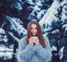 Frau in einem blauen Pelzmantel trinkt Tee foto