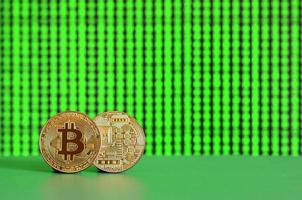 Auf der grünen Fläche im Hintergrund des Displays liegen zwei goldene Bitcoins, die den Prozess des Schürfens der Kryptowährung zeigen foto