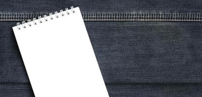 weißes notizbuch mit sauberen seiten, die auf dunkelblauem jeanshintergrund liegen. Bild mit Kopierbereich foto
