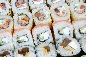 Nahaufnahme vieler Sushi-Rollen mit verschiedenen Füllungen. Makroaufnahme gekochter klassischer japanischer Speisen. Hintergrundbild