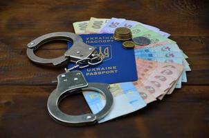 ein Foto eines ukrainischen ausländischen Passes, eine bestimmte Menge ukrainisches Geld und Polizeihandschellen. das Konzept der Verhaftung ukrainischer illegaler Einwanderer bei Bestechungsversuchen