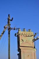 alter und veralteter elektrischer Transformator vor dem Hintergrund eines wolkenlosen blauen Himmels. Vorrichtung zur Verteilung der Versorgung mit Hochspannungsenergie foto