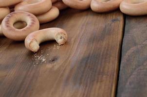 viele frische gelbe bagels liegen auf der oberfläche des alten dunklen holzes. eine beliebte Art von Mehlprodukten. eine der traditionellen russischen Leckereien für Tee foto