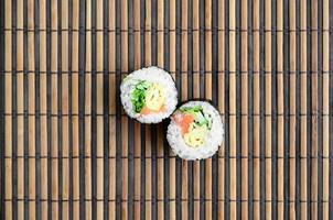 Sushi-Rollen liegen auf einer Nähmatte aus Bambusstroh. traditionelles asiatisches essen. Ansicht von oben. flacher Laienminimalismus mit Kopierraum foto