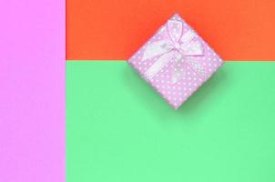 kleine rosa geschenkbox liegen auf texturhintergrund von mode pastelltürkis, rot und rosa farben papier foto