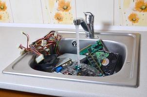 Hardware in der Küchenspüle unter dem metaphorischen Konzept der Reinigung des Wasserflusscomputers foto