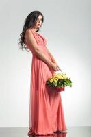 Modefrau im roten Kleid, das einen Blumenkorb hält foto