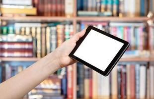 Hand hält Tablet-PC in der Bibliothek foto
