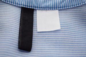 leeres schwarz-weißes etikett für kleidung auf blauem stoffstrukturhintergrund foto