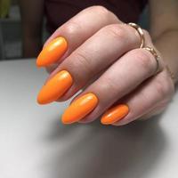 stilvolle, trendige orange weibliche maniküre.hände einer frau mit orangefarbener maniküre auf den nägeln foto