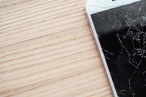 zerbrochenes Glas des Handy-Bildschirms auf Holzhintergrund foto