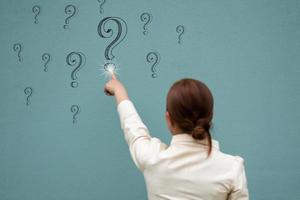 Eine Geschäftsfrau berührt das Fragezeichen an der blauen Wand, das Frage- und Antwortkonzept konzentriert sich auf die Wand foto