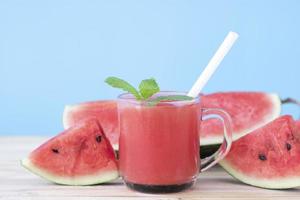 Wassermelonengetränk und Scheiben auf blauem Hintergrund