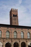 palazzo del potesta auf der piazza maggiore bologna, beschattet von der kirche san petronio und dem asinelli-turm im hintergrund foto