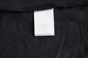 leeres weißes Wäschepflegeetikett auf schwarzer Stoffstruktur foto