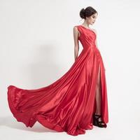 junge Schönheitsfrau im flatternden roten Kleid. weißer Hintergrund. foto