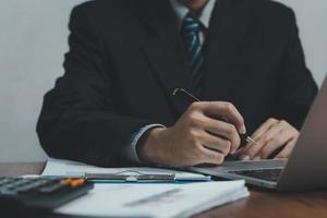 Hand mit Stift schreiben Papierkram Geschäftsdokument Finanzinvestition oder Unterschrift Vertrag Job und Versicherung auf dem Schreibtisch.