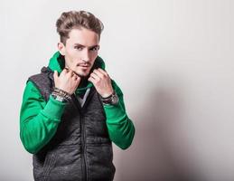 attraktiver junger Mann in grauer Weste & grünem Pullover. foto