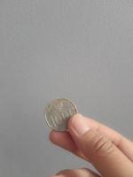 isoliertes Foto einer Hand, die eine Münze mit tausend Rupiah hält.