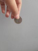 isoliertes Foto einer Hand, die eine Münze mit tausend Rupiah hält.