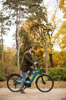 junger Mann mit Elektrofahrrad im Herbstpark foto