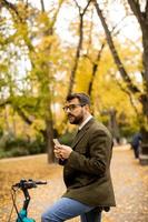 junger Mann mit Elektrofahrrad im Herbstpark foto