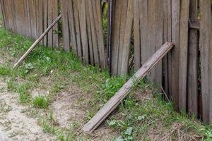 Alter staubiger wackeliger Holzzaun mit Plankenstützen und Gras hautnah mit selektivem Fokus foto