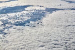 luftwolkengebilde blick über die wolkenspitze zu schneebedeckten flüssen, straßen, städten und feldern, winterluft foto