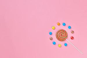 süßer lutscher und süßigkeiten auf rosa hintergrund foto
