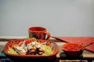 mexikanische Flautas mit Salat, Avocado, Sahne, Sauce und frischem Wasser foto