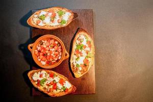 mexikanische molletes, traditionelles essen mit brot, bohnen, käse, tomate und chili foto