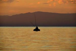 schöner baikalsee, ein boot mit fischern bei sonnenuntergang foto