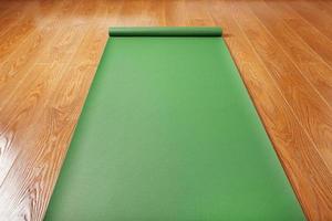 Grüne Yogamatte auf Holzboden entfaltet. gesunder lebensstil, fitness, sport.