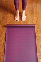 eine frau legt eine lila yogamatte auf den holzboden. foto
