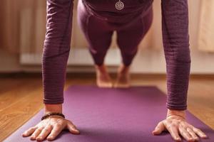 das mädchen macht yoga im asana-stand auf einer lila matte. foto