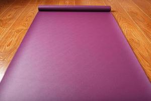 Auf dem Holzboden liegt eine lilafarbene Yogamatte mit einer Ganapati-Figur foto