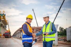 ingenieure schütteln sich auf der baustelle die hände, bauarbeiter in schutzuniform schütteln sich auf der baustelle die hände mit dem vorarbeiter foto