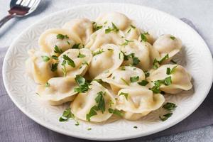 traditionelle pelmeni, ravioli, mit fleisch gefüllte knödel auf teller, russische küche foto