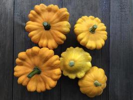 fünf orange Patissons auf einem hölzernen Hintergrund. Herbsternte von Orangenkürbis. gesundes lebensmittelkonzept. Sicht von oben. flach liegen. foto