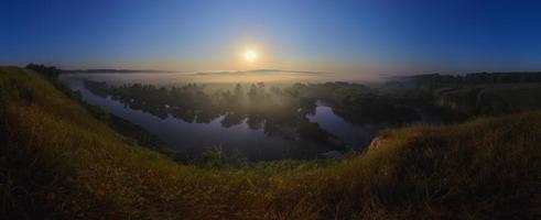 nebliger sonnenaufgang am fluss im sommer weitwinkelpanorama. foto