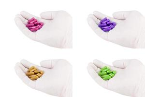Satz Hand im medizinischen Handschuh, der farbige organische med. Kapseln hält, die auf weißer Hintergrundnahaufnahme lokalisiert werden foto