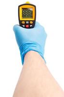 rechte hand in blauem medizinischem latexhandschuh mit gelbem kontaktlosem infrarotthermometer isoliert auf weiß, mockup-anzeigezustand mit allen an