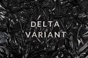 Wörter Delta-Variante mit silbernen Metallbuchstaben auf zerknittertem schwarzem Plastiktütenhintergrund foto