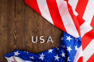 das wort usa mit silbernen metallbuchstaben auf holzbrettoberfläche unter zerknitterter flagge der vereinigten staaten von amerika gelegt foto