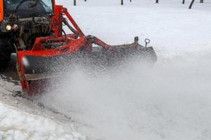 Schneereinigung. Schneeräumtraktor, der mit einer speziellen rotierenden Rundbürste Schnee vom Bürgersteig räumt, foto