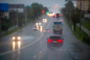 Defokussiertes Bild des Straßenautoverkehrs am Abend nach Regen - Blick von der Straße. foto