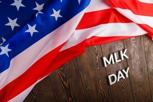 das wort mlk day mit silbernen metallbuchstaben auf holzoberfläche mit zerknitterter usa-flagge an der oberseite foto