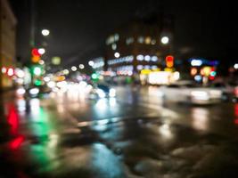 Defocused Night Rain City Street View mit Autos, die die Straße überqueren foto