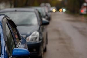 Autos, die auf einer nassen, schmutzigen Straße geparkt sind - Tele-Nahaufnahme mit selektivem Fokus foto